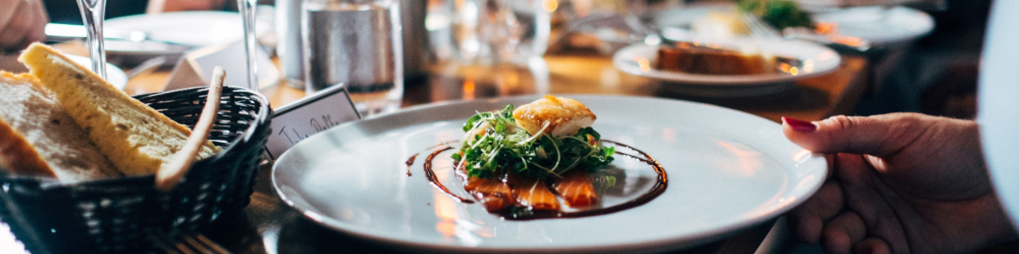 A dining table with gourmet food, wine glasses, and bread in a restaurant setting, creating an elegant and social atmosphere.