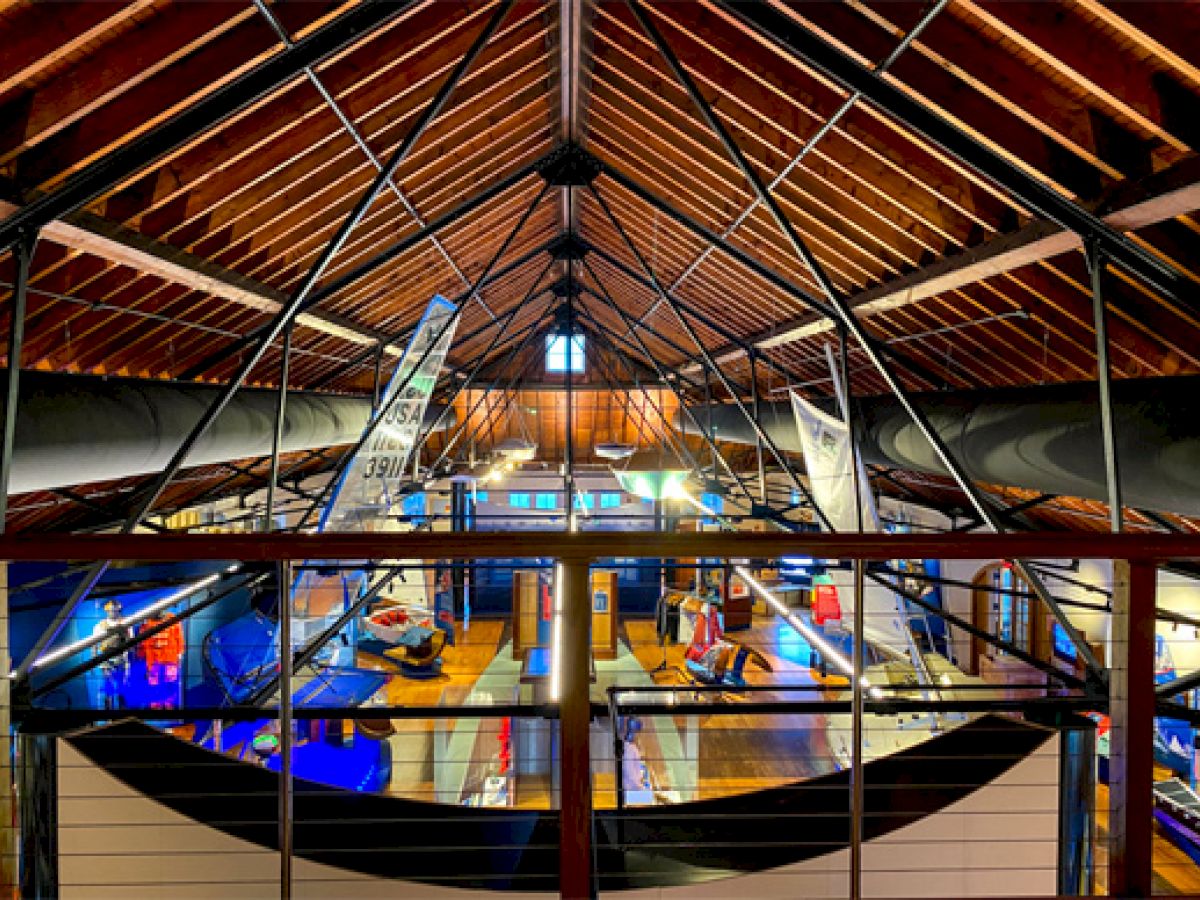 This image shows a modern interior with exposed beams, industrial design, and bright lighting over a multi-level workspace or exhibition area.