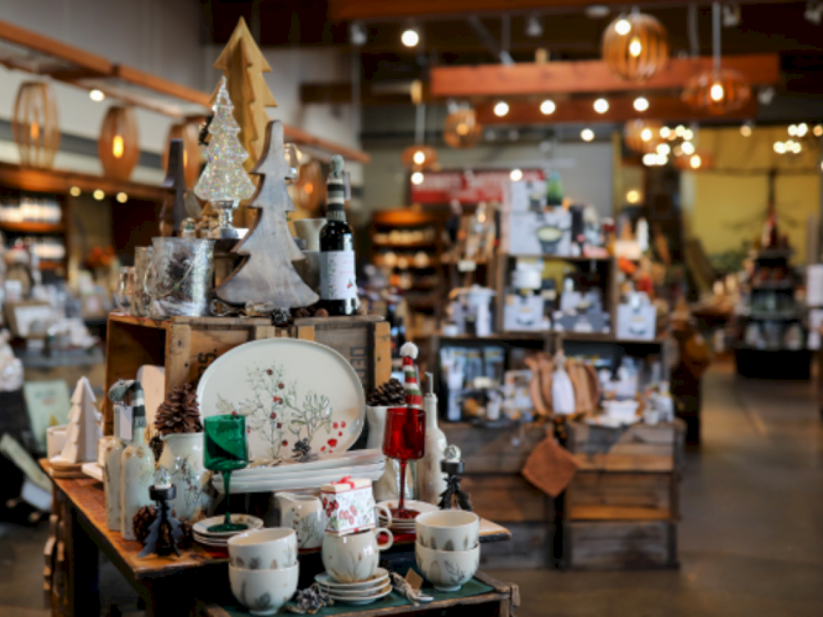 A cozy store with holiday-themed decorations, Christmas trees, and tableware on display under warm lighting.